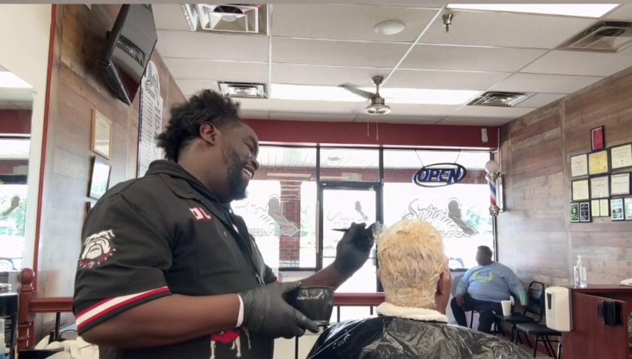 Barber applying hair color to a client inside Supremes Barbershop