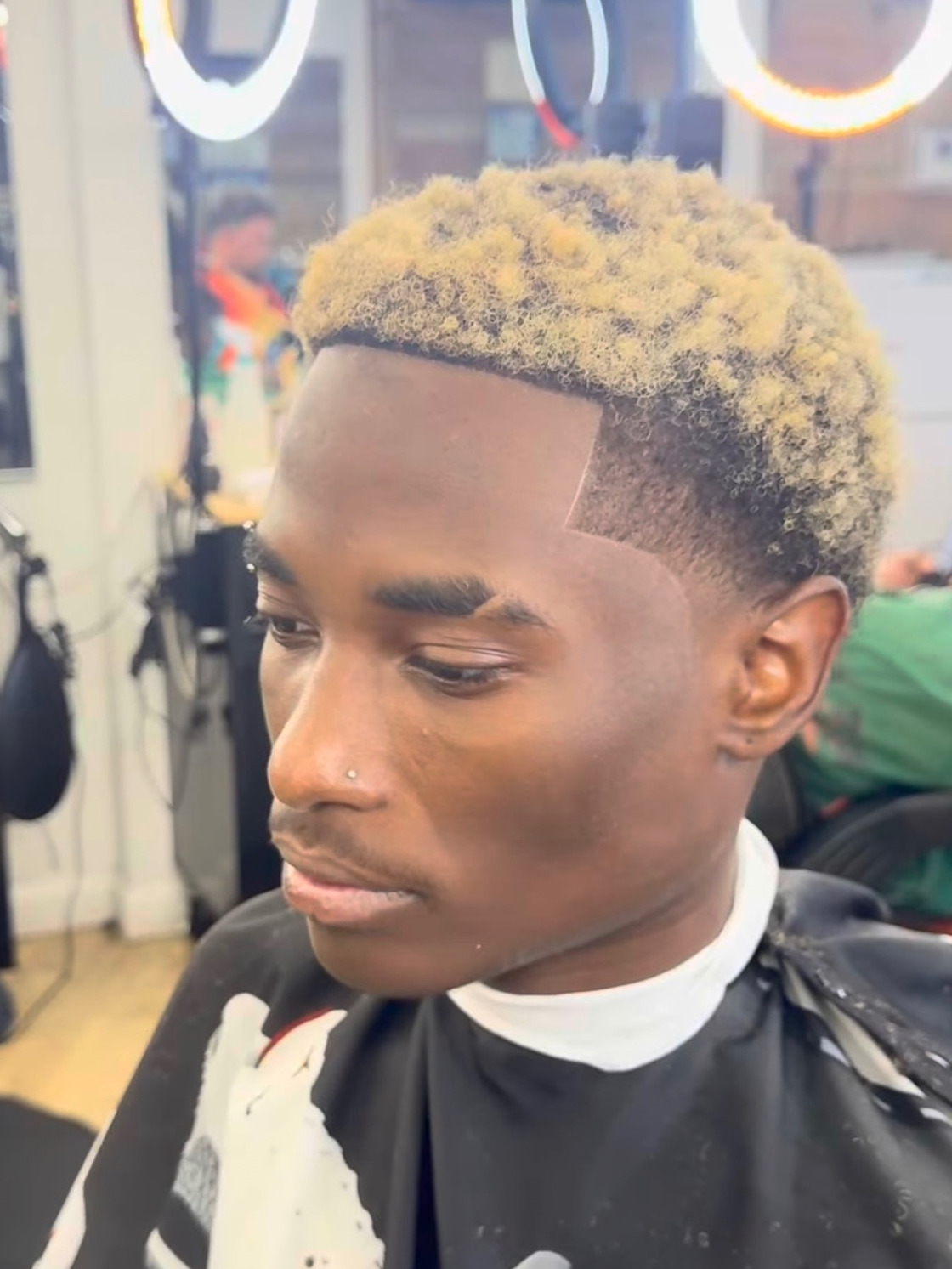 Blonde-dyed curly top with a sharp line-up and clean fade